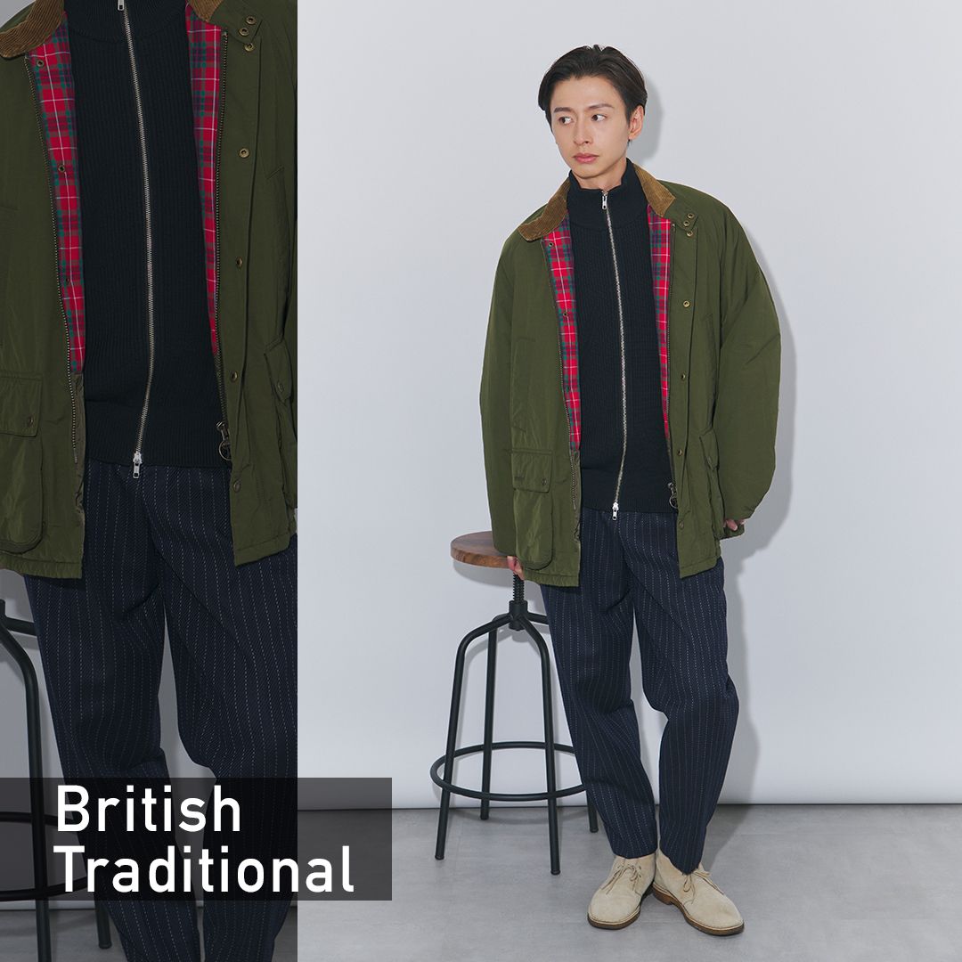 オリーブのコートにブラックのジップニットとネイビーのストライプパンツを合わせたブリトラスタイル